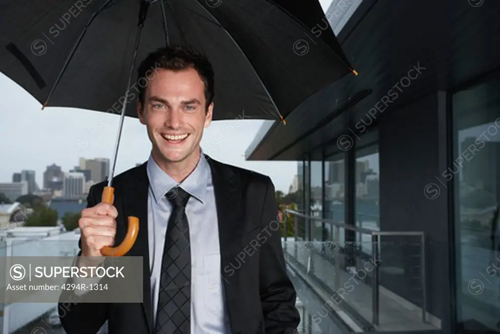 Smiling businessman standing in the rain
