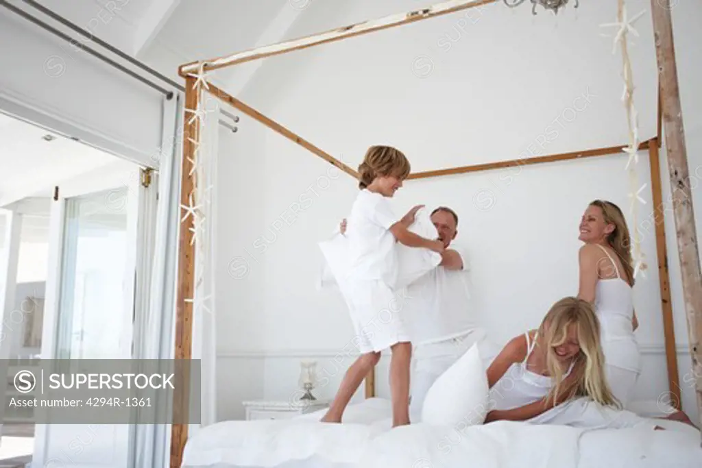 Happy family pillow fighting in bed