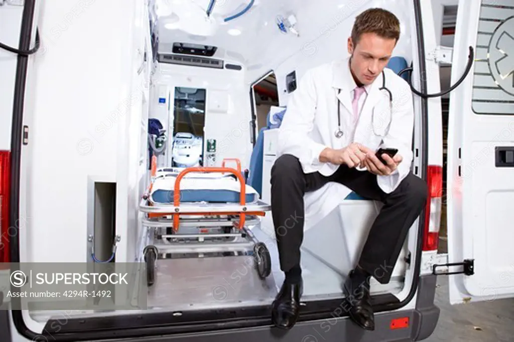 Doctor in ambulance car using cell phone