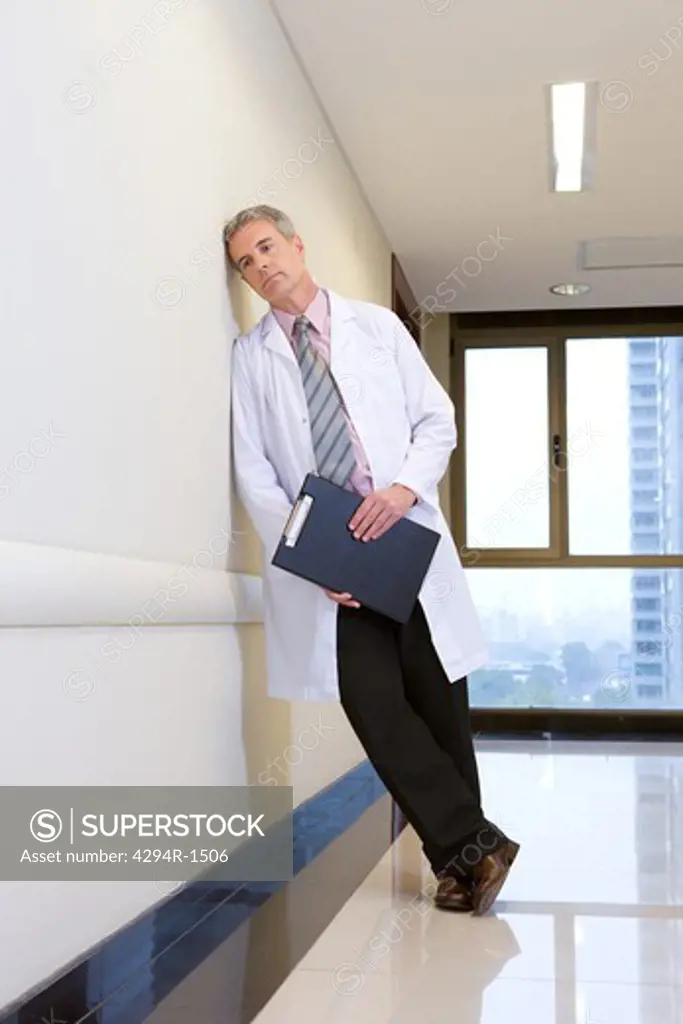 Doctor leaning against wall on hospital corridor