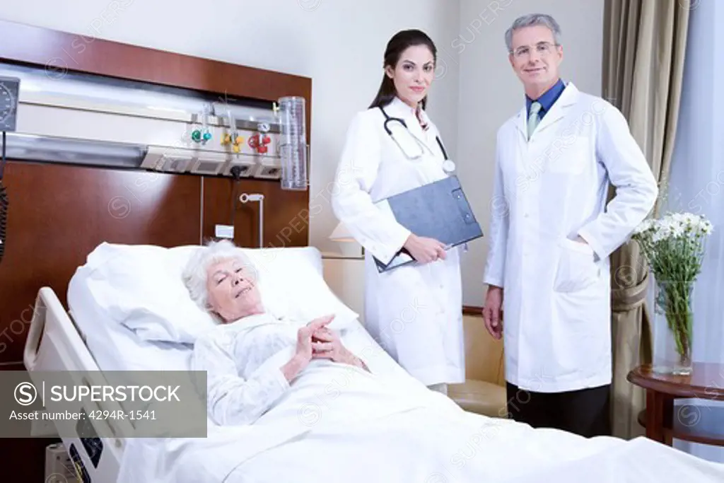 Doctors and senior woman in hospital bed