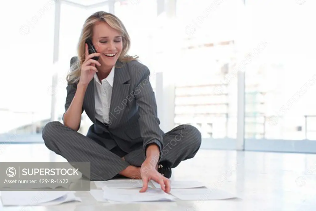 Businesswoman with cell phone and documents on office floor