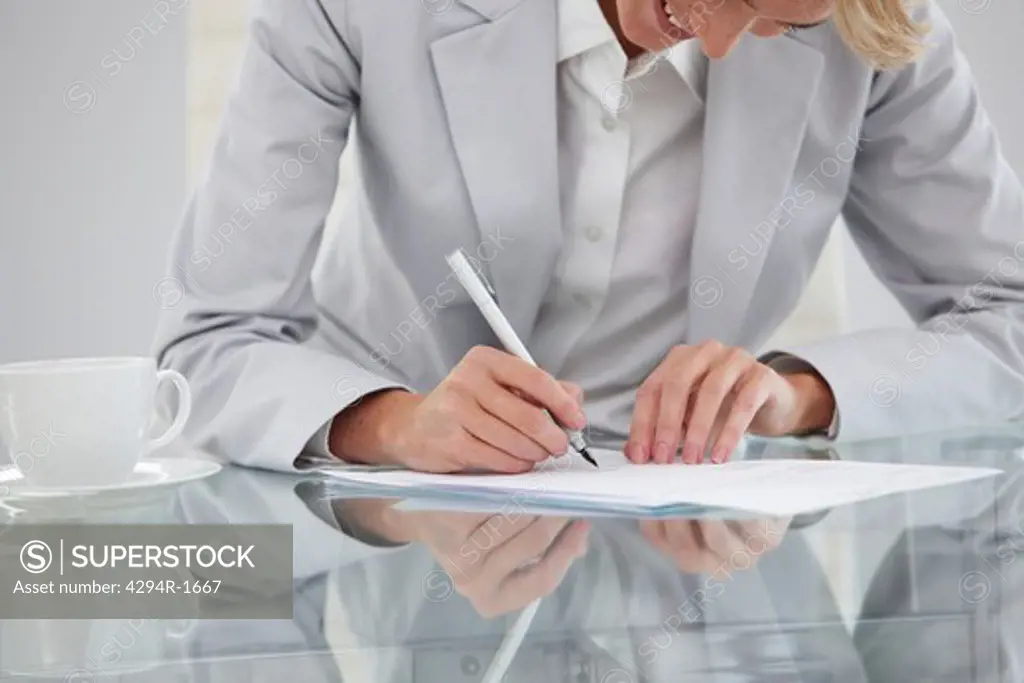 Businesswoman at desk signing contract