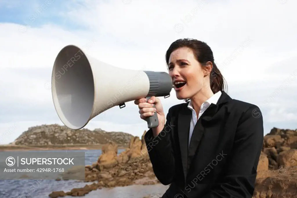 Businesswoman with megaphone in remote landscape