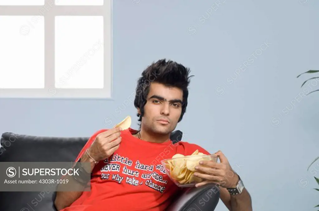 Young man holding potato chip, portrait
