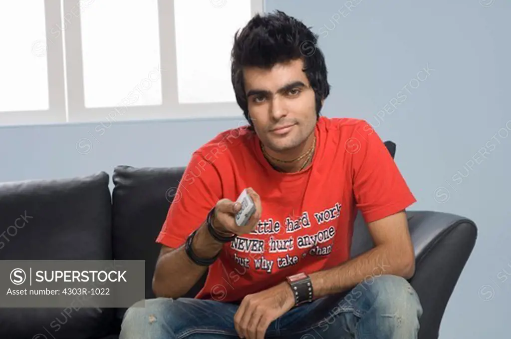 Young man holding remote control, portrait