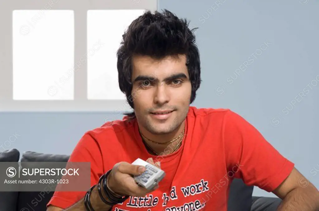 Young man holding remote control, portrait