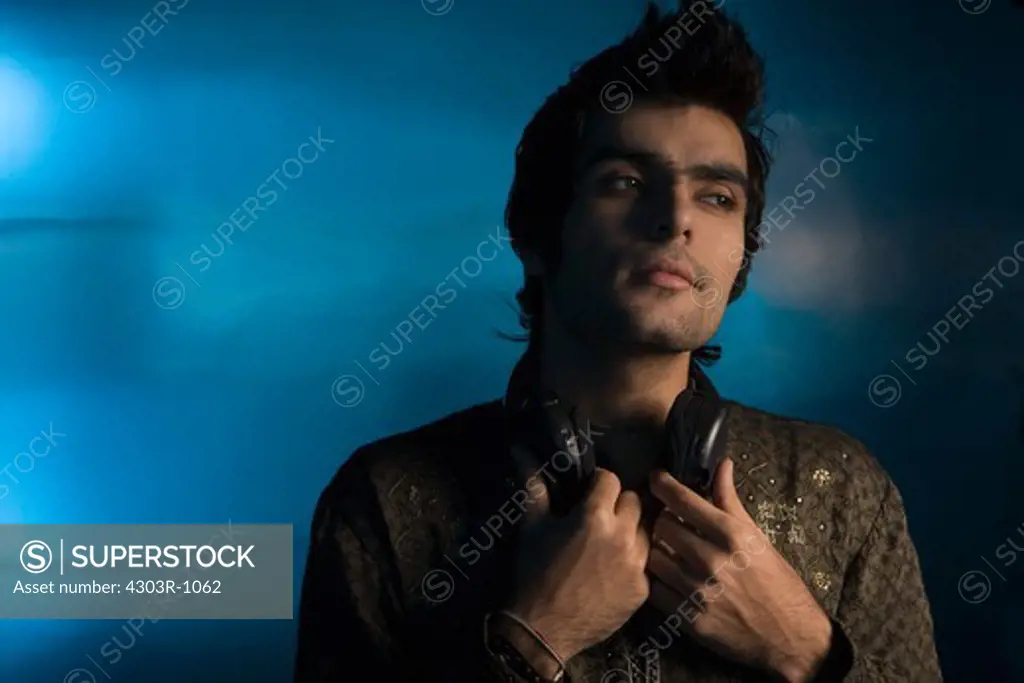 Young man holding headphones around neck