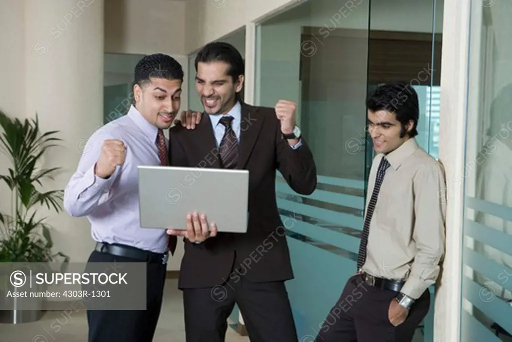 Businessmen looking at laptop in office