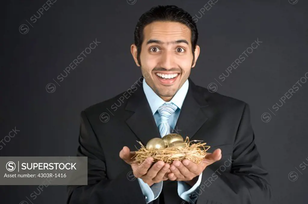 Businessman holding nest with golden egg, portrait