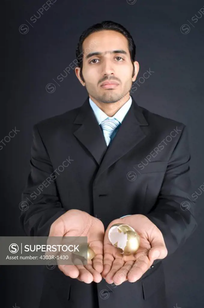 Businessman holding broken golden egg in cupped hands