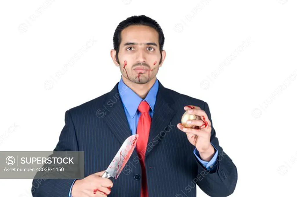 Businessman holding knife with golden egg, portrait