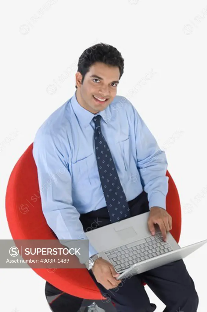 Young businessman using laptop, elevated view, portrait