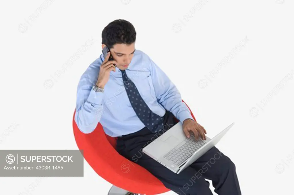 Young businessman with laptop using mobile phone, elevated view