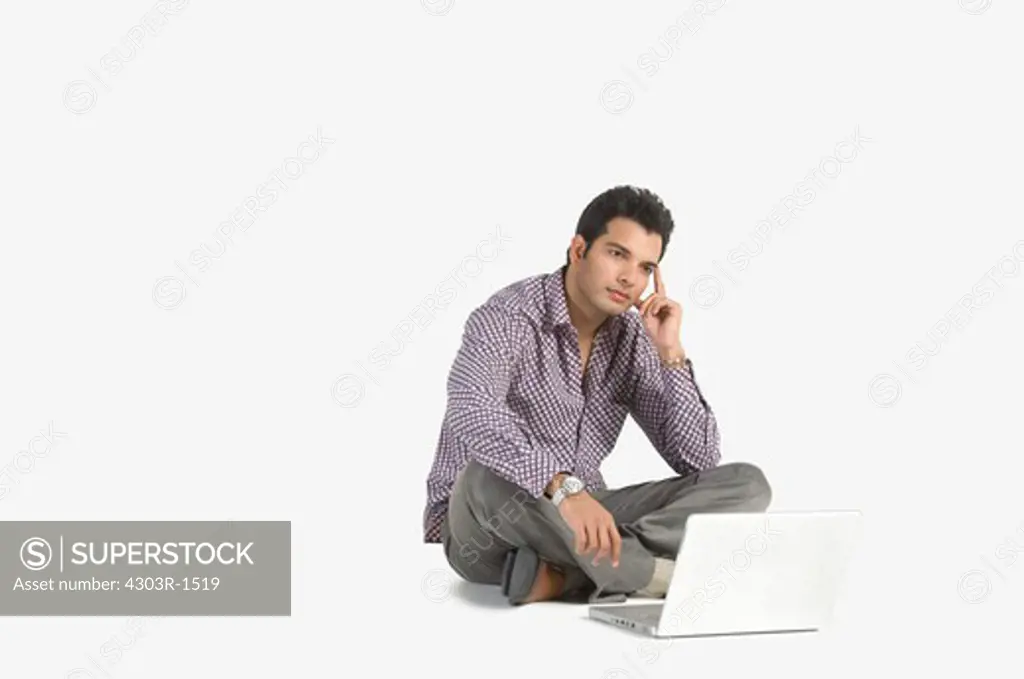 Young man sitting with laptop, looking away