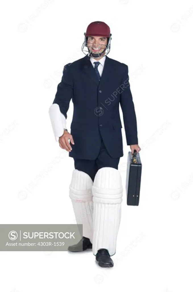 Businessman wearing sports helmet and cricket pad, smiling, portrait