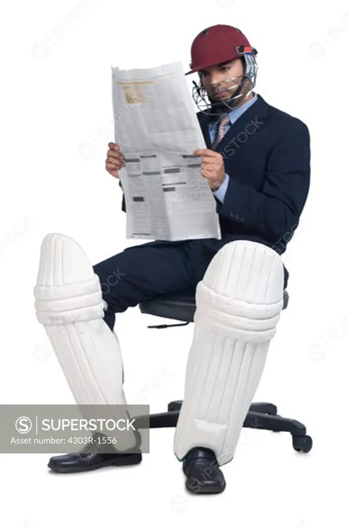 Businessman wearing sports helmet, reading newspaper