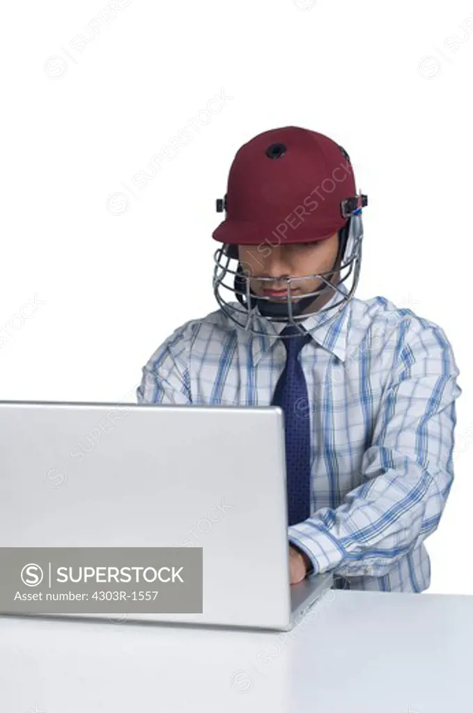 Businessman wearing sports helmet, using laptop