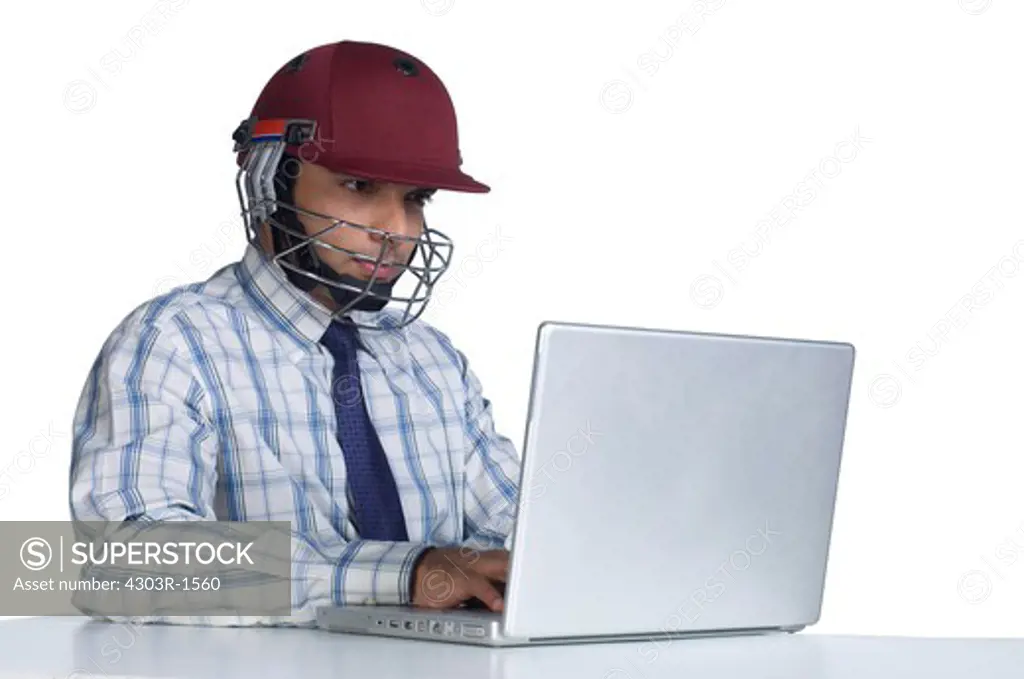 Businessman wearing sports helmet, using laptop, close-up