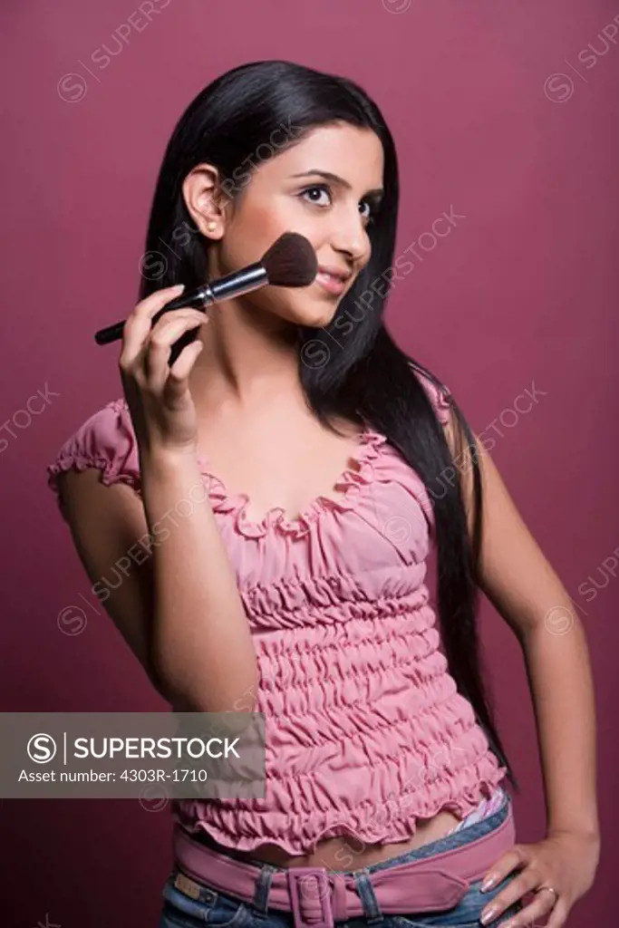 Young woman applying holding blusher brush