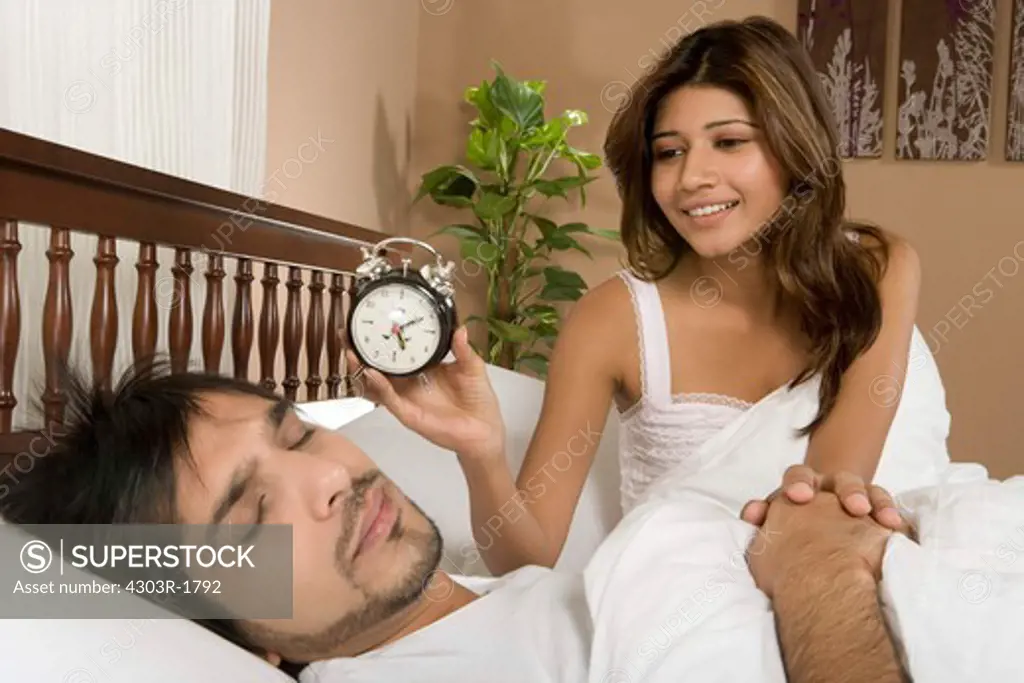 Wife waking up husband with clock
