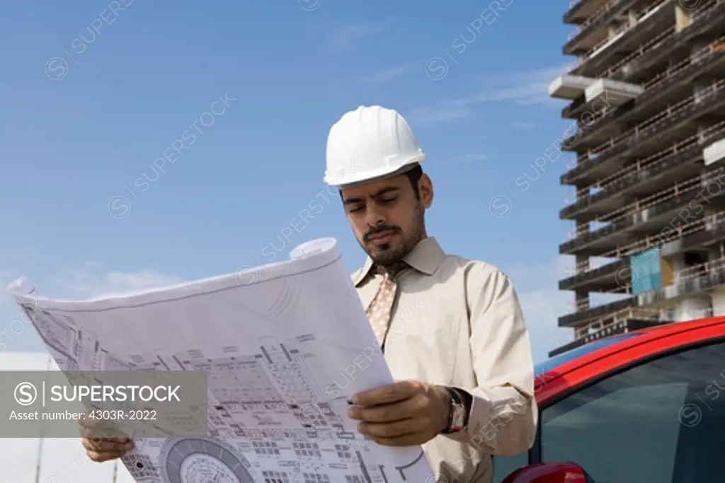 Architect looking at blueprint at construction site
