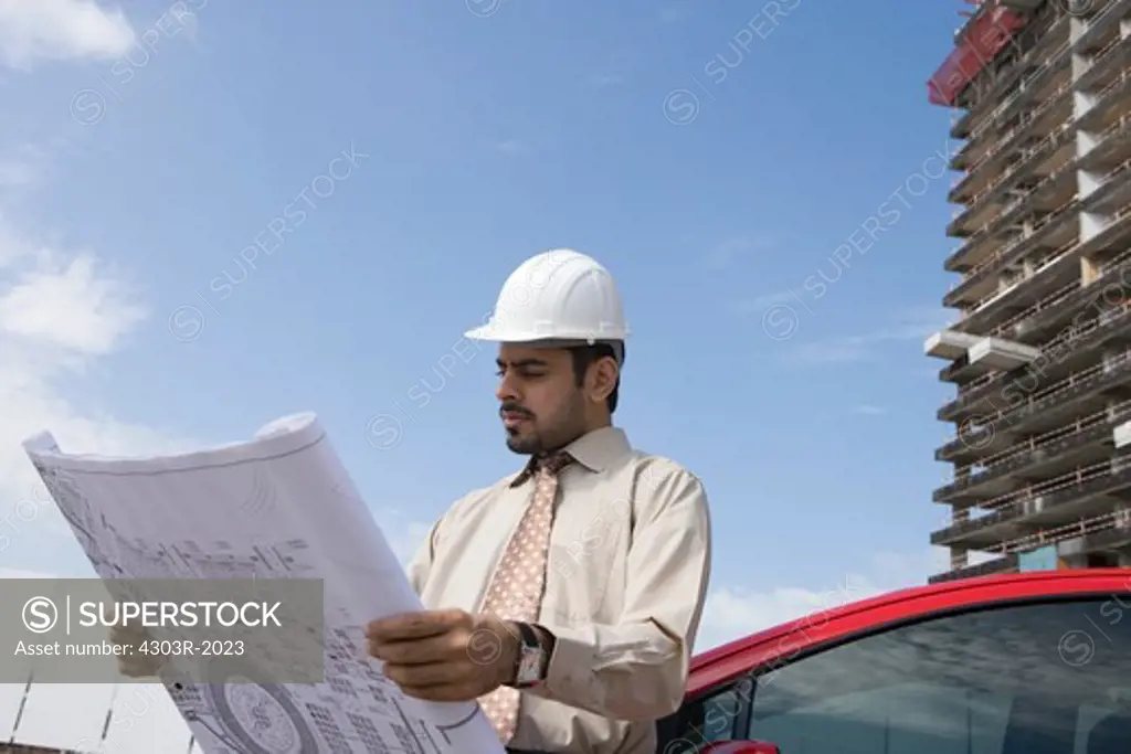Architect looking at blueprint at construction site