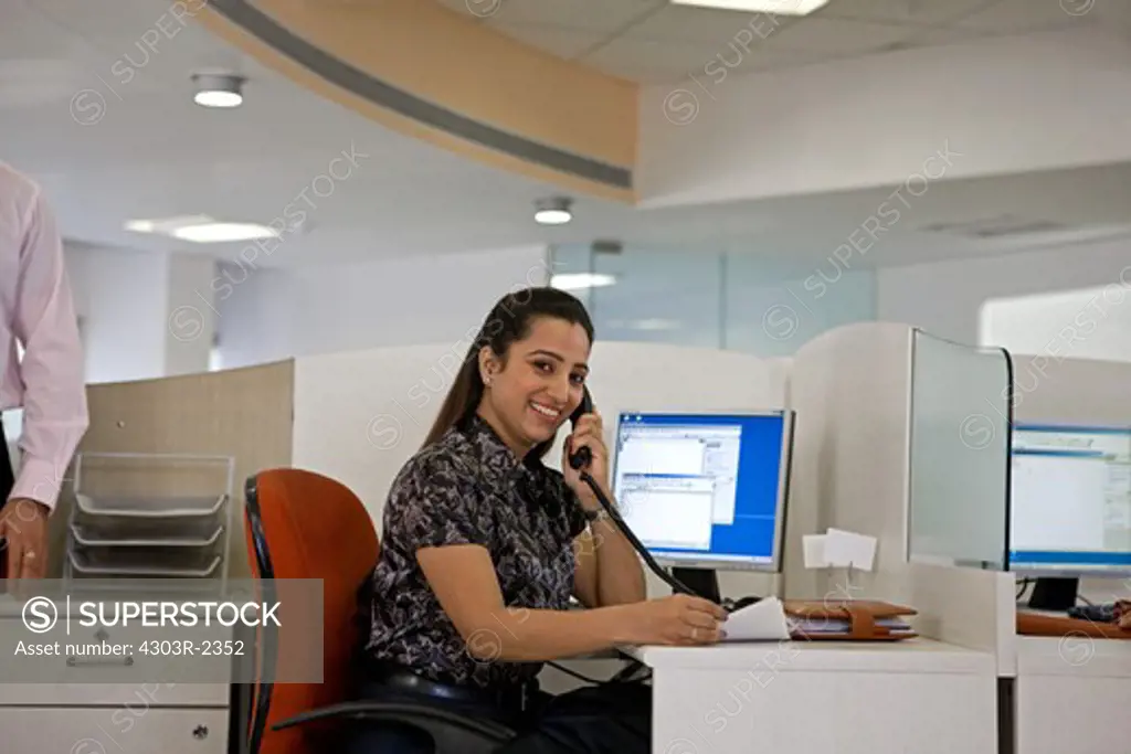Businesswoman talking on telephone at the office, smiling
