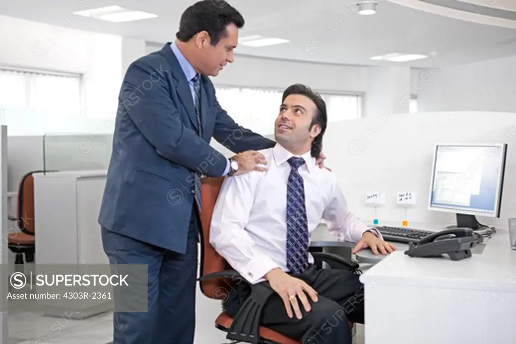 Two businessmen talking in the office, smiling
