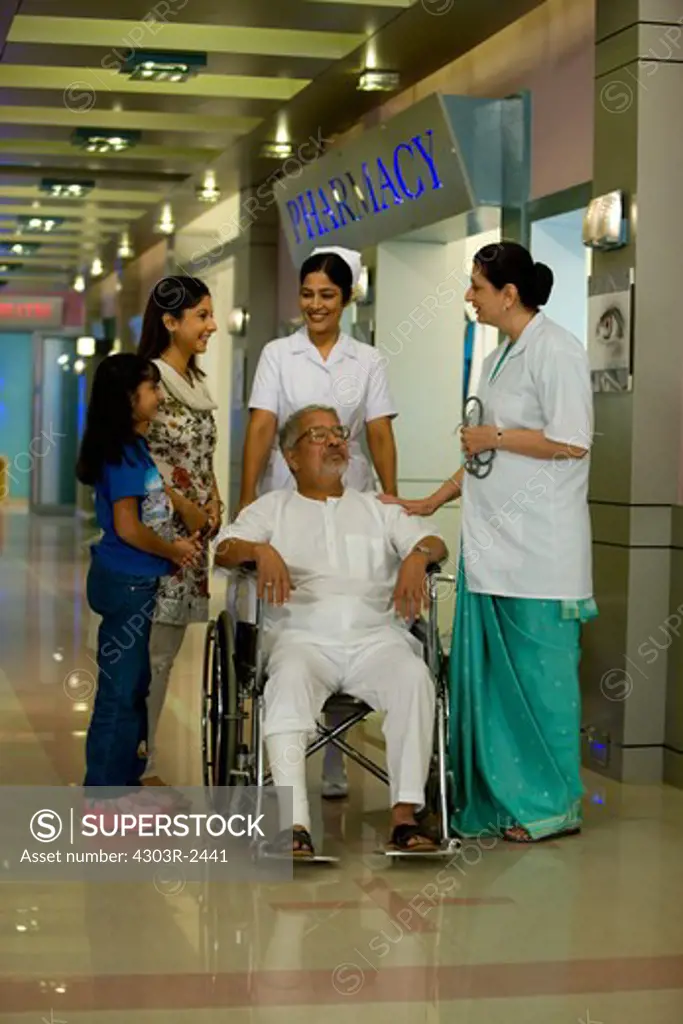 Senior man sitting on a wheelchair visits by his two daughters in the hospital