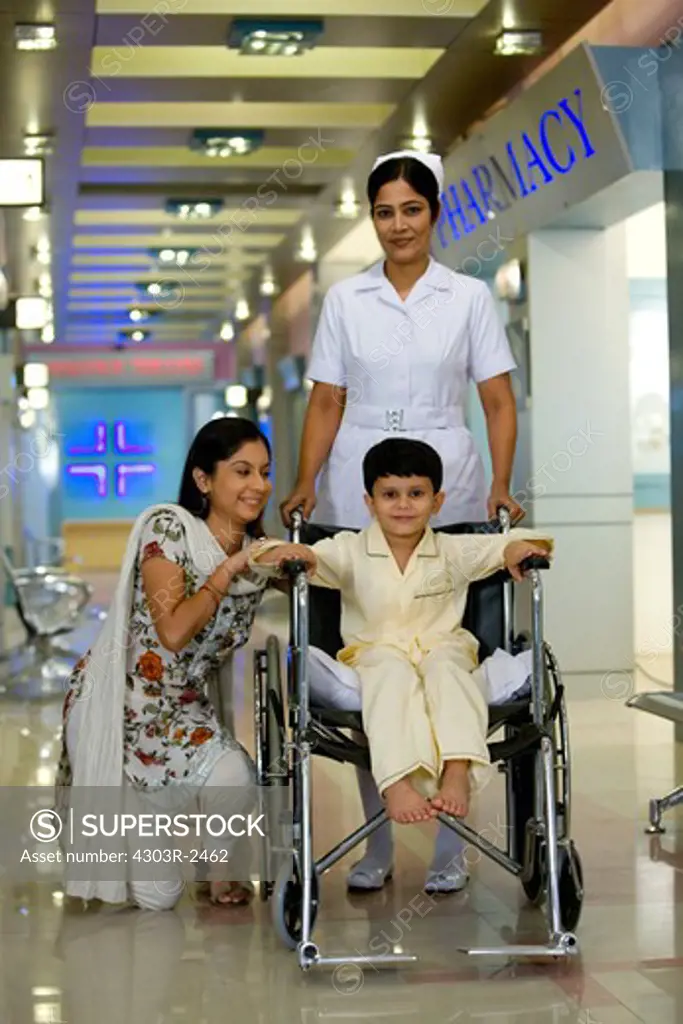Mother and son in a hospital corridor, boy sitting on a wheelchair