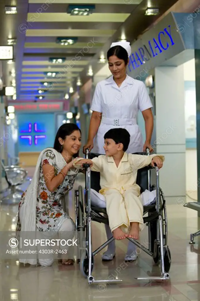 Mother and son in a hospital corridor, boy sitting on a wheelchair