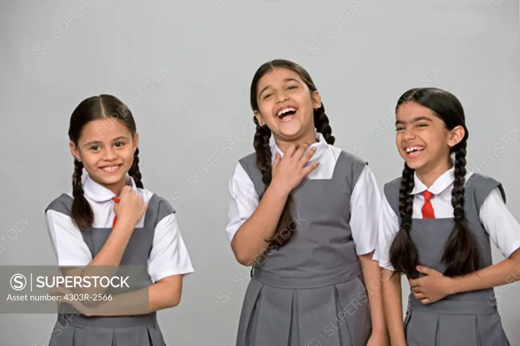 Three girls wearing school uniform laughing together