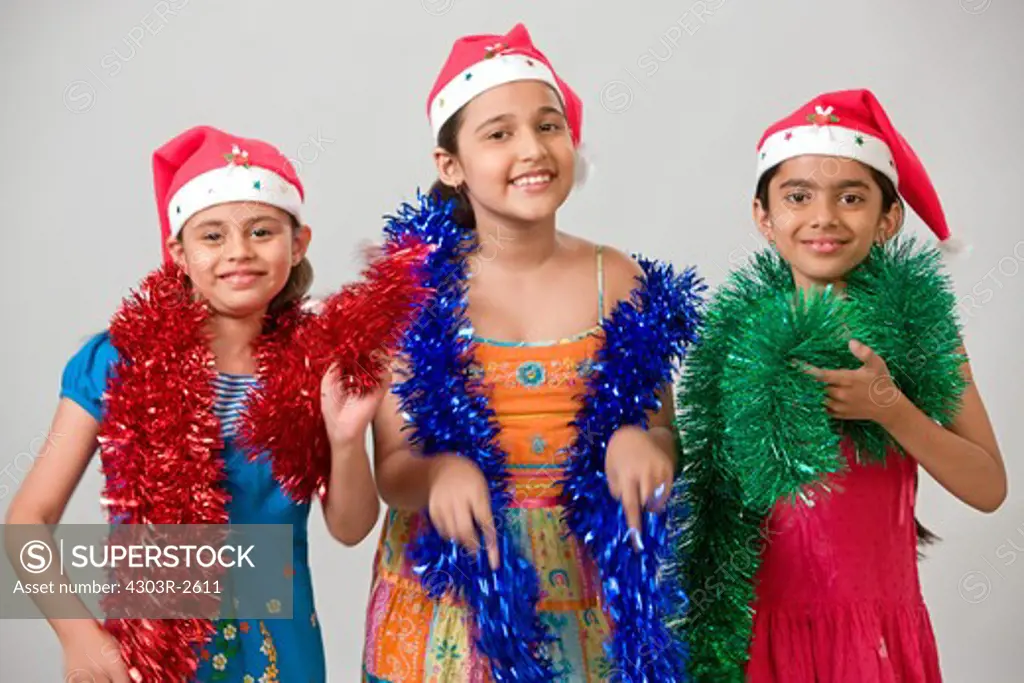 Three girls wearing santa hat, looking at the camera