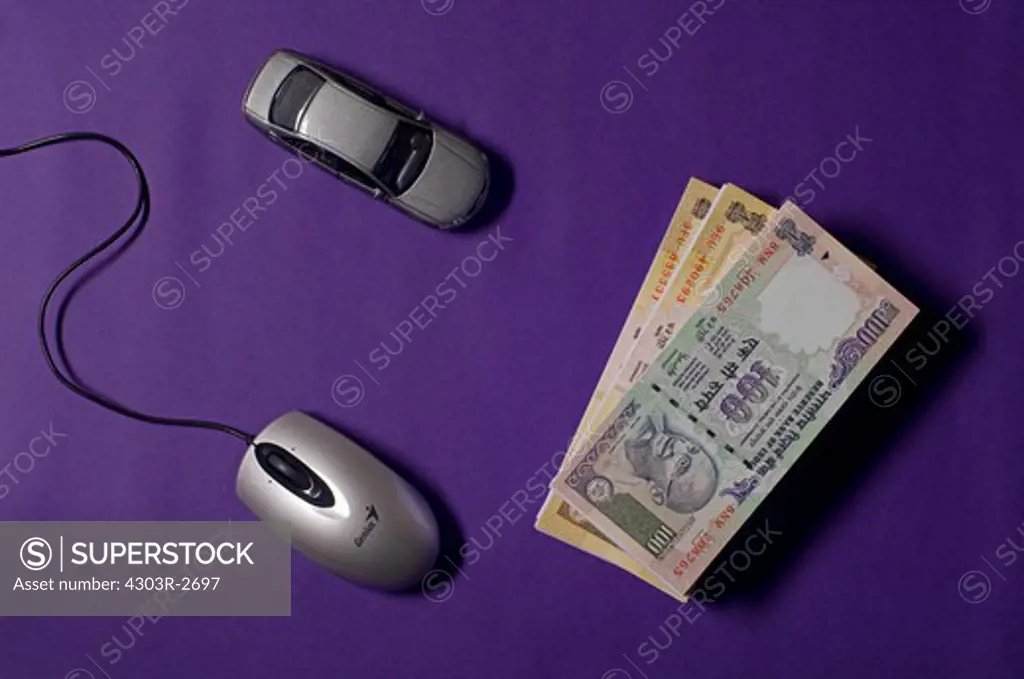 Bundles of indian rupee banknotes with toy car and compute mouse