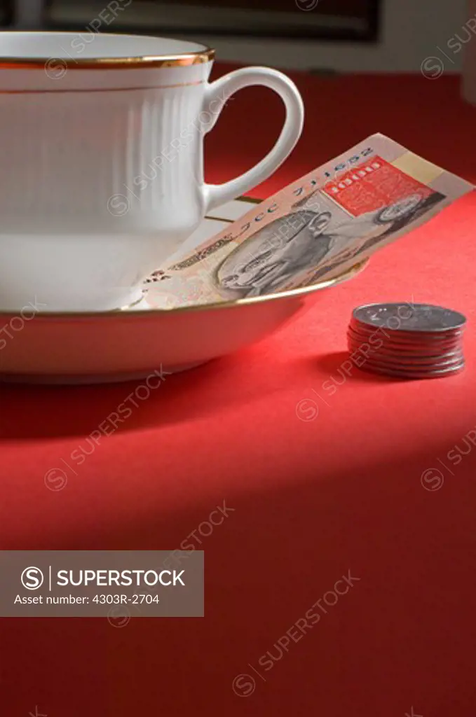 Cup and saucer with indian rupees at the side