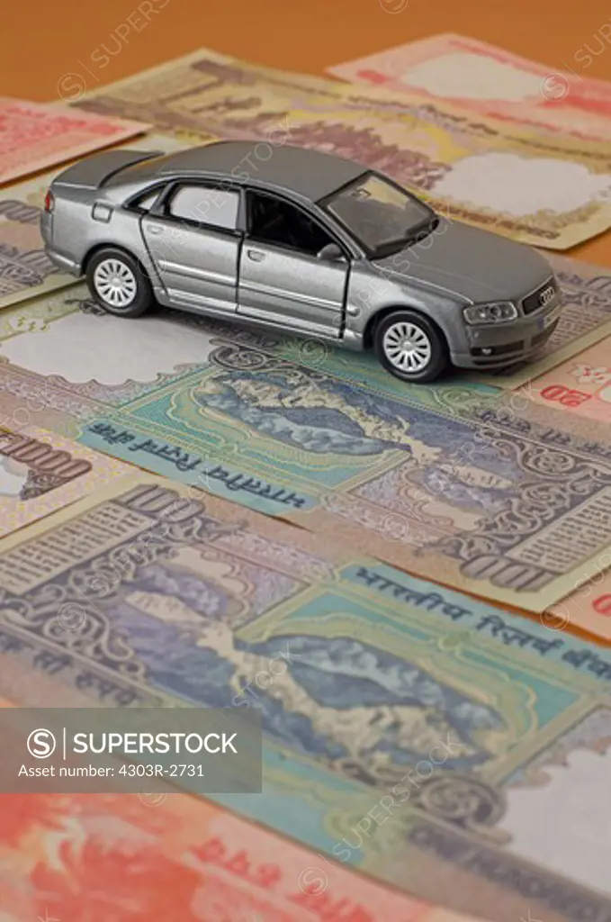Toy car on top of indian rupee banknotes