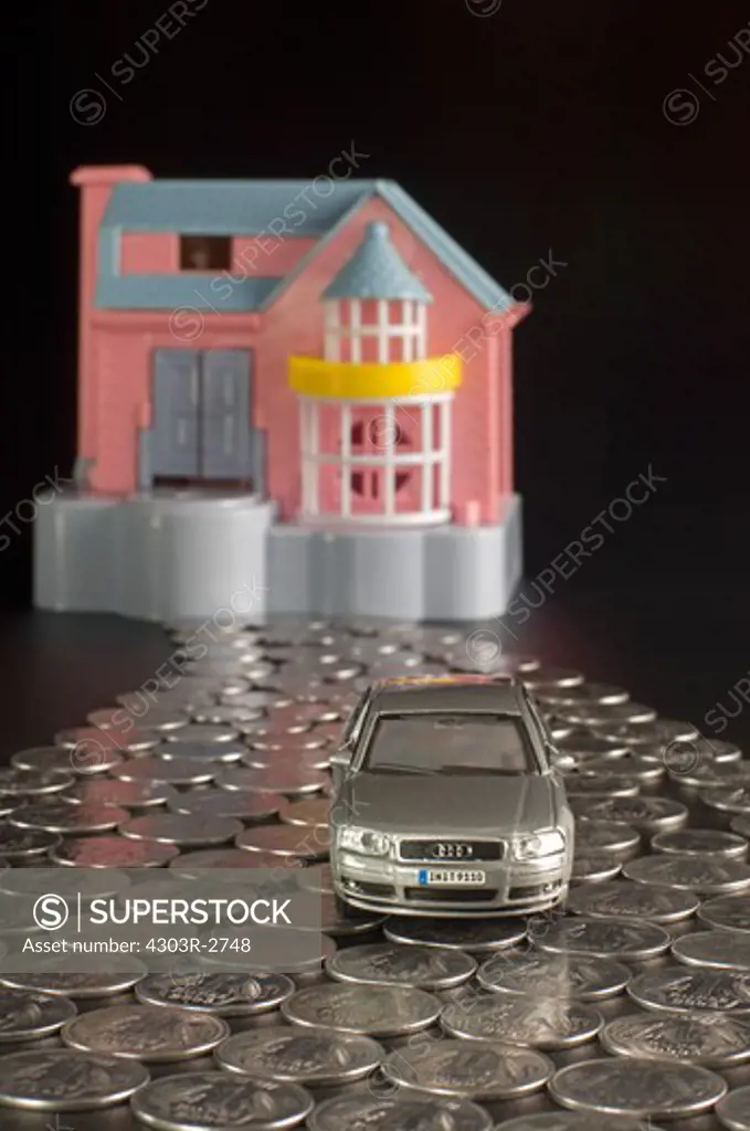 Doll house and toy car with indian rupee coins in a shape of a road