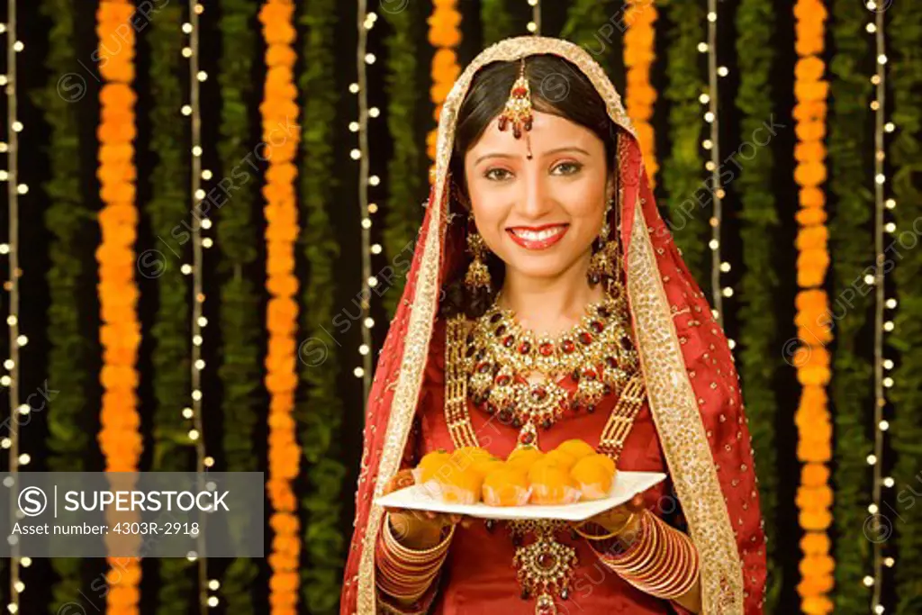 Indian bride carrying a platter of sweets