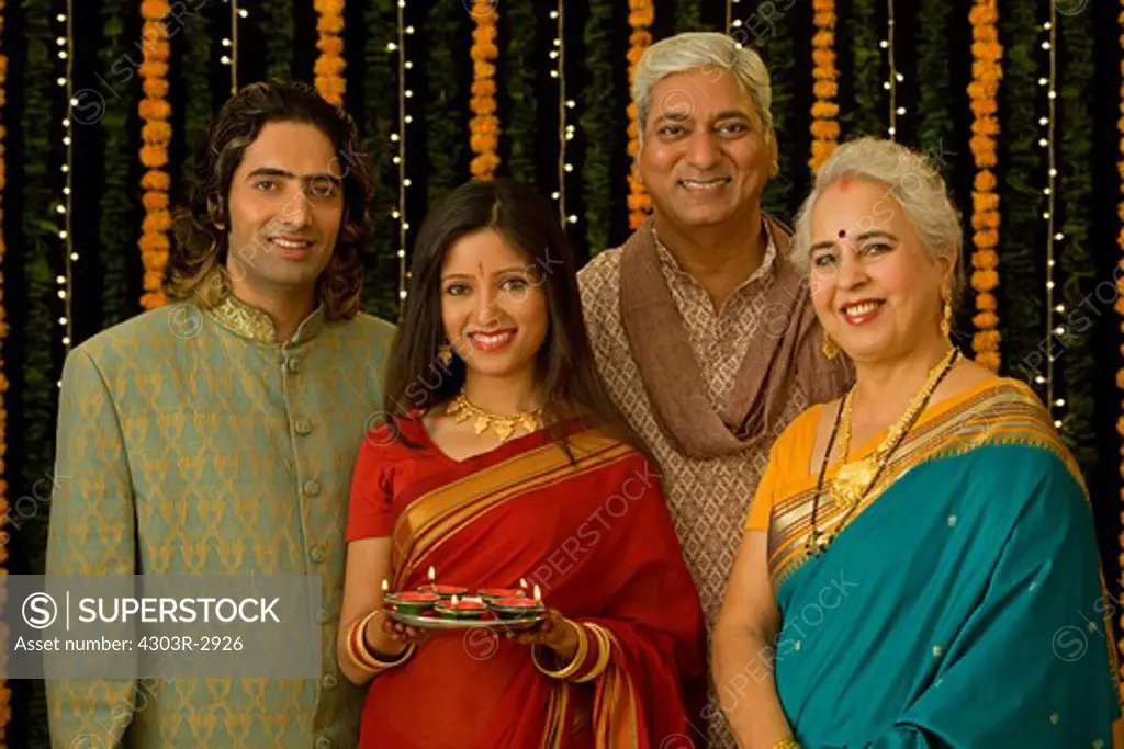 Indian family smiling, young woman holding a platter of candles