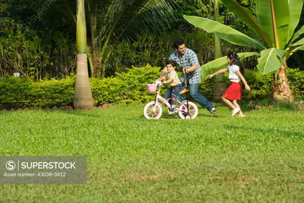 Son learning bicycle with her father, daughter chasing