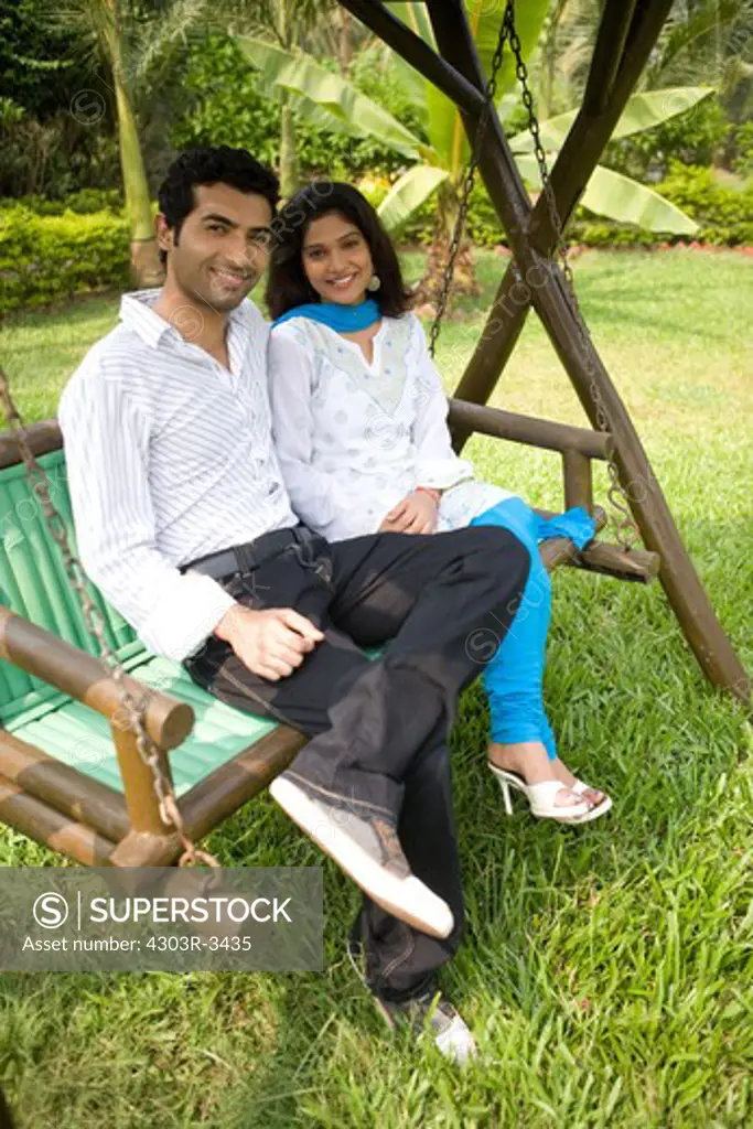 Couple sitting on the swing in their garden