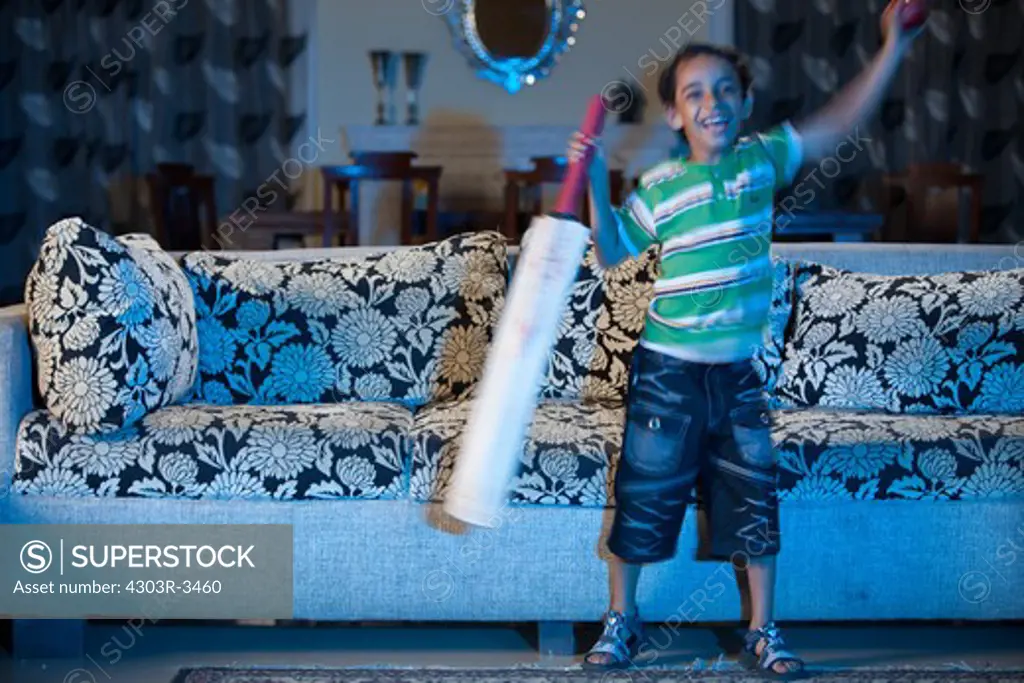 Boy with cricket bat and ball, watching sports program in the television