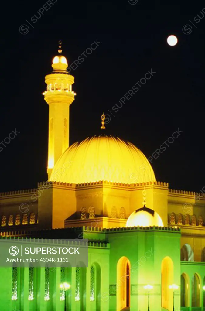 Low angle view of a dome and a minaret of a mosque seen under the full moon.