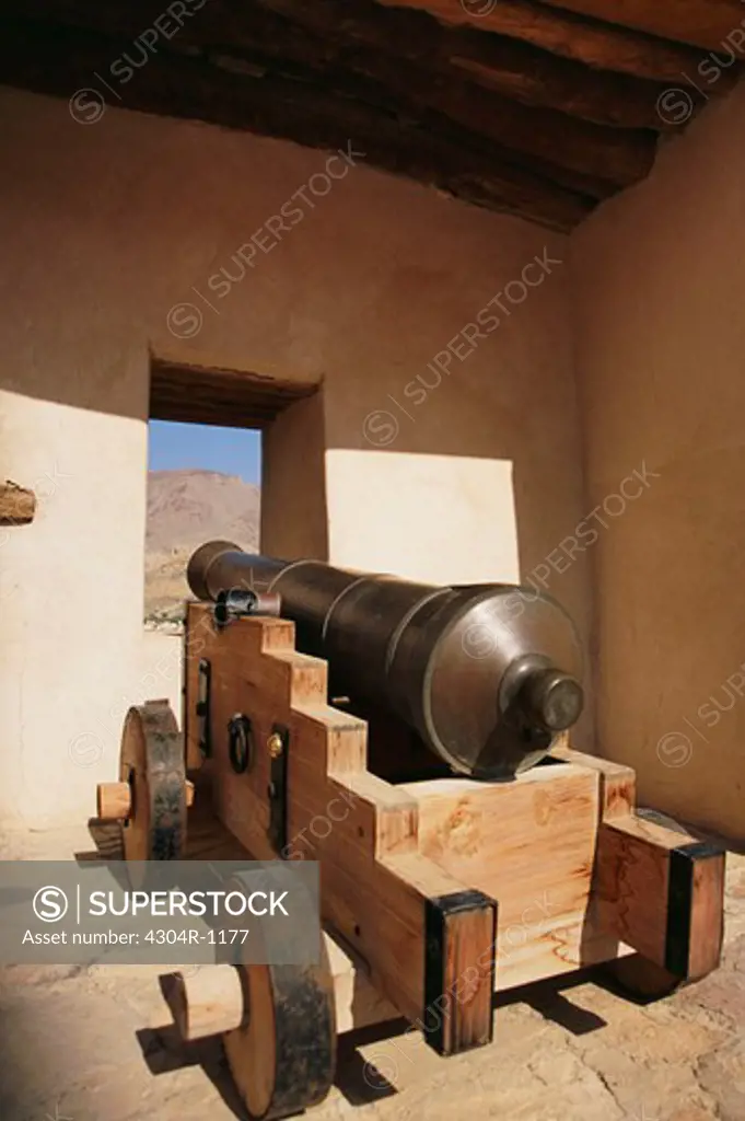 A cannon is placed near the window inside an ancient fort.