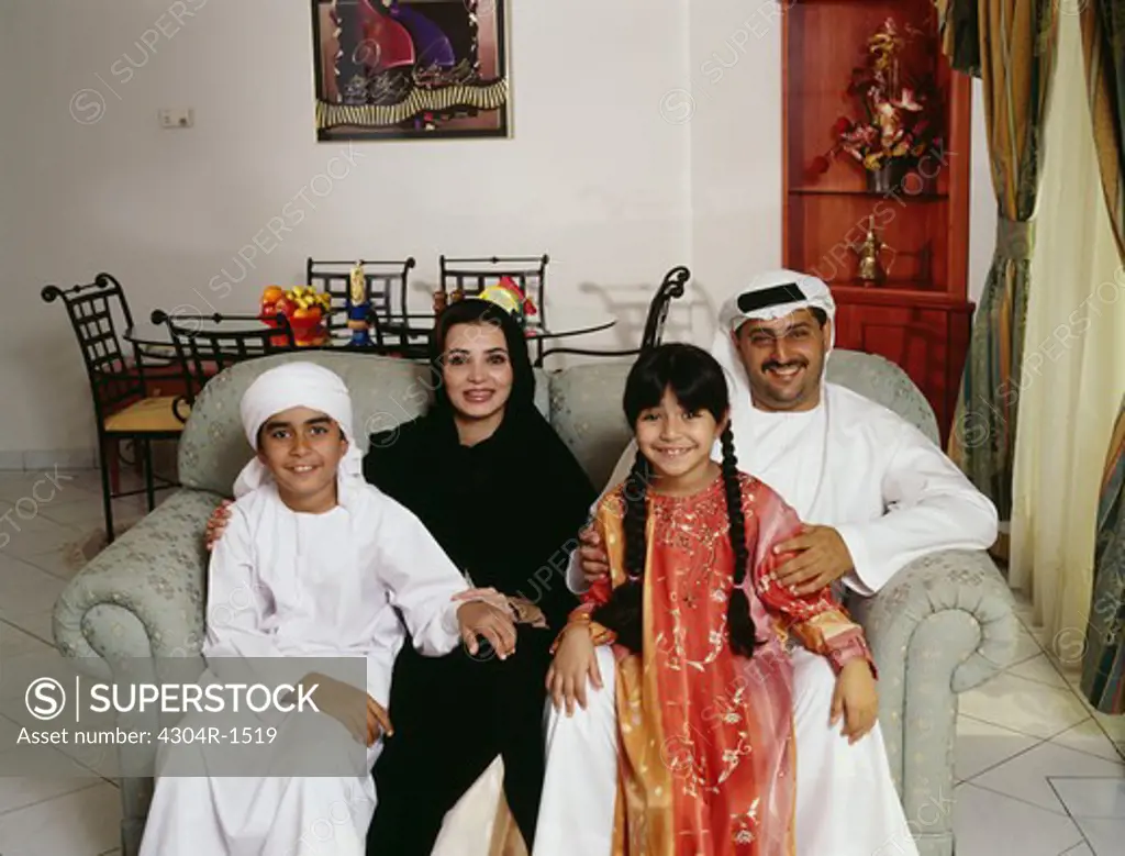 A happy Arab family smiles at the camera at their residence.
