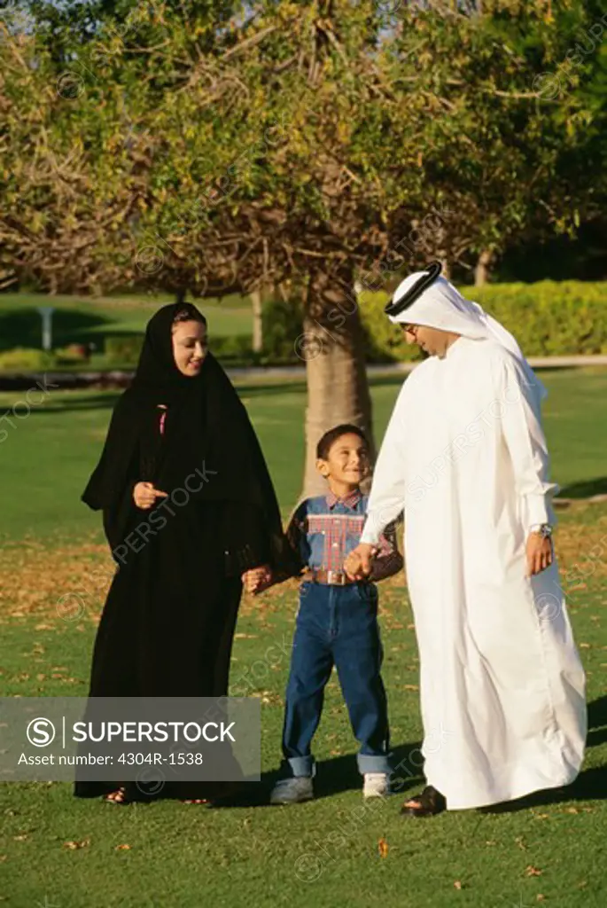 A boy with his mother and father taking a stroll in the park.
