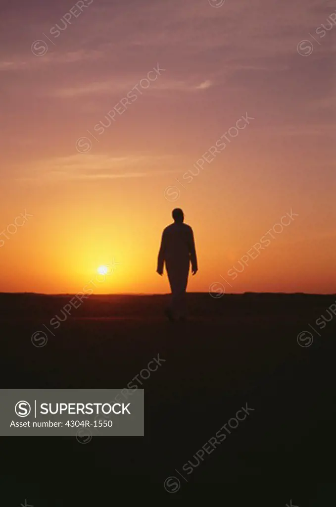 A man seen walking at sunset.