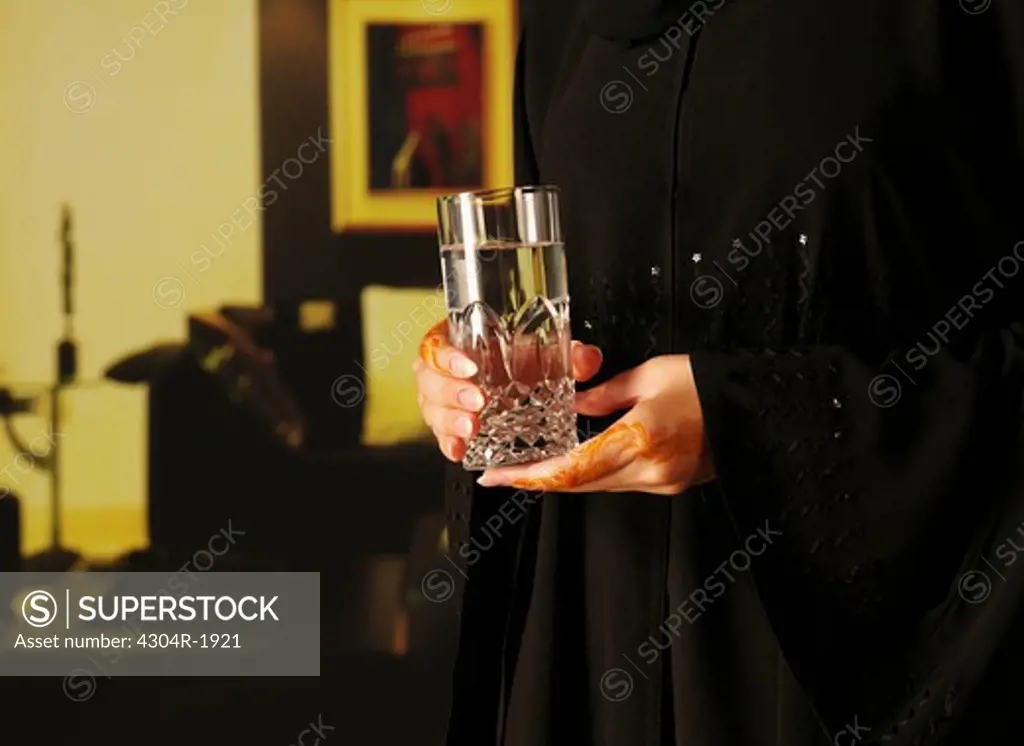 Arab lady with henna on hands holding glass of water
