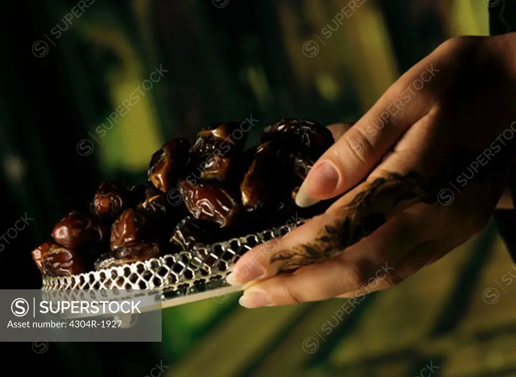 Arab women henna on hands holding dates